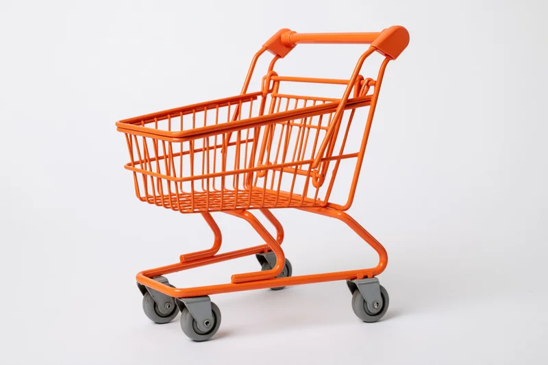 Small orange metal shopping cart empty on white background