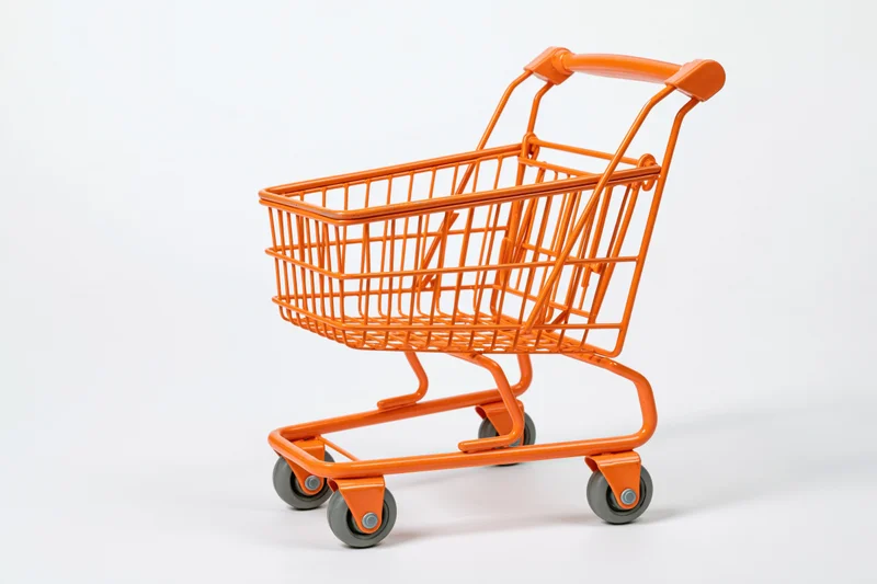 Small orange metal shopping cart empty on white background