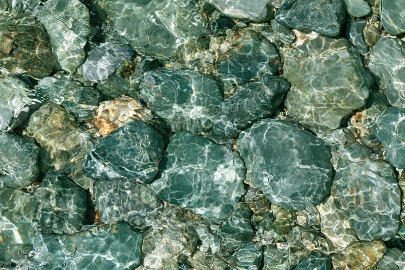 Clear shallow water over smooth river stones in a natural riverbed setting