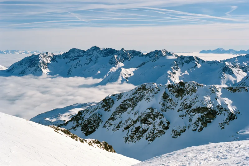 Snow-covered alpine peaks rising above a thick sea of clouds