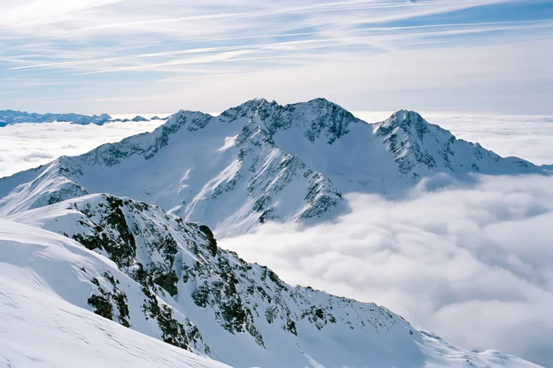Snow-covered alpine peaks rising above a thick sea of clouds