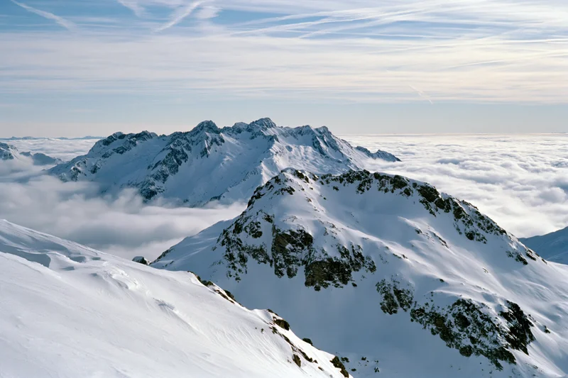 Snow-covered alpine peaks rising above a thick sea of clouds