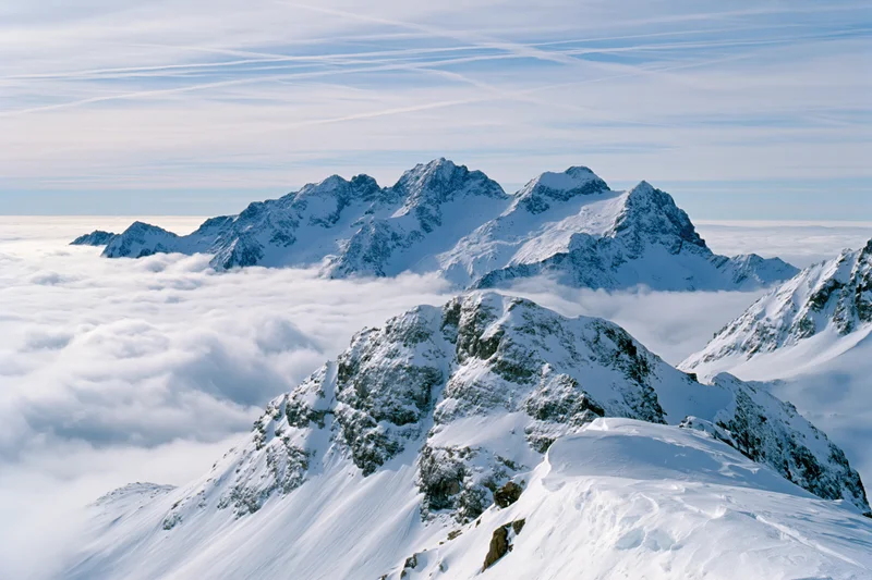 Snow-covered alpine peaks rising above a thick sea of clouds