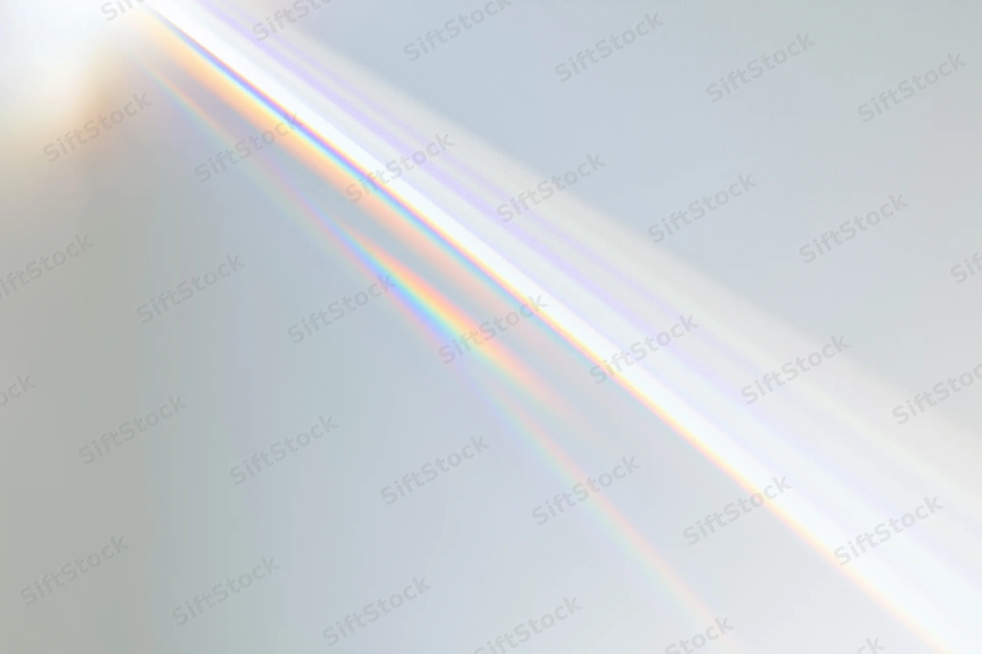 Sunlight refracting through a prism casting a rainbow spectrum across a light surface