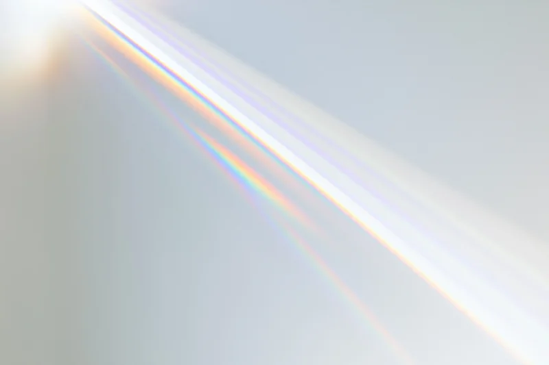 Sunlight refracting through a prism casting a rainbow spectrum across a light surface