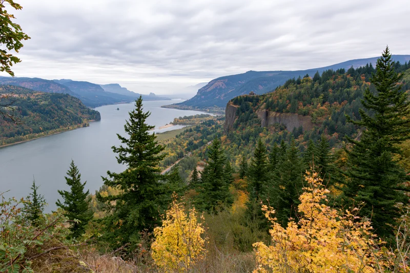 Wide-angle view of a river gorge in autumn surrounded by forested mountains and colorful foliage