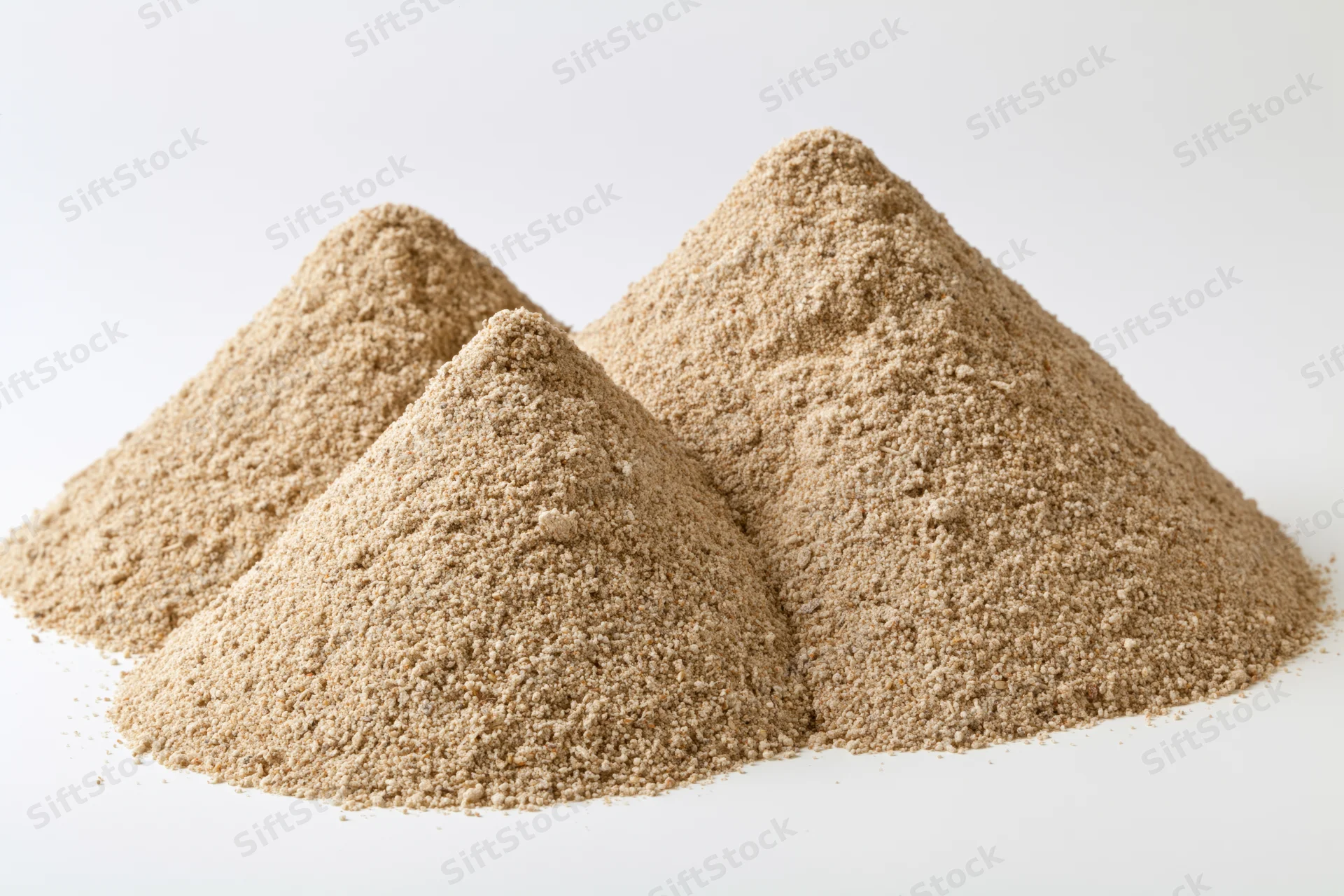 Three mounds of dry construction sand piled together on white background