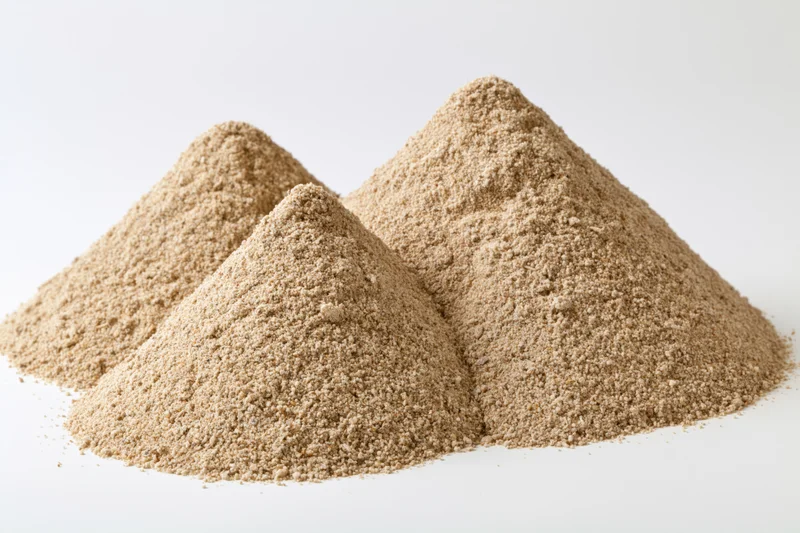 Three mounds of dry construction sand piled together on white background