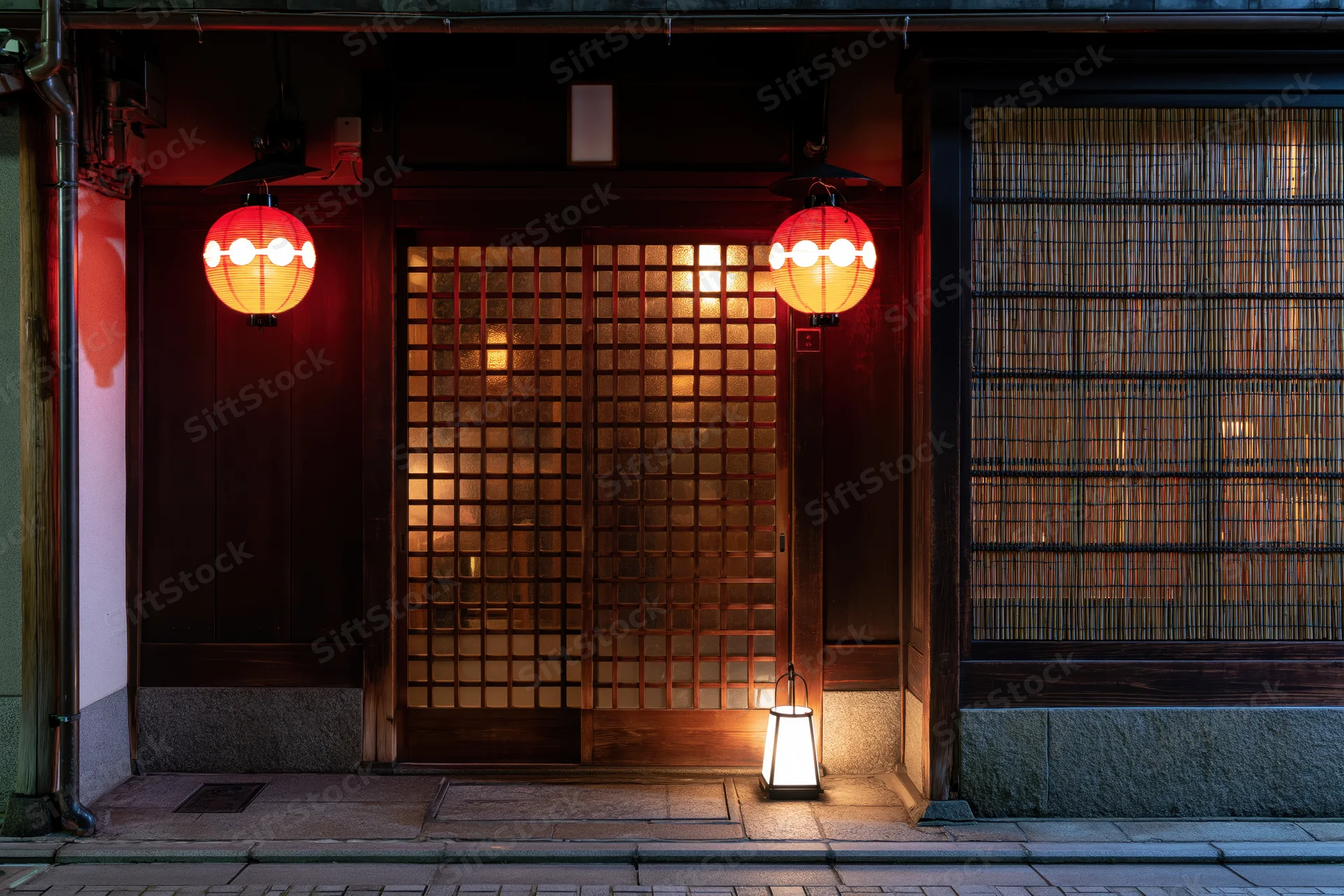 Traditional japanese restaurant entrance at night with glowing red lanterns and wooden grid door