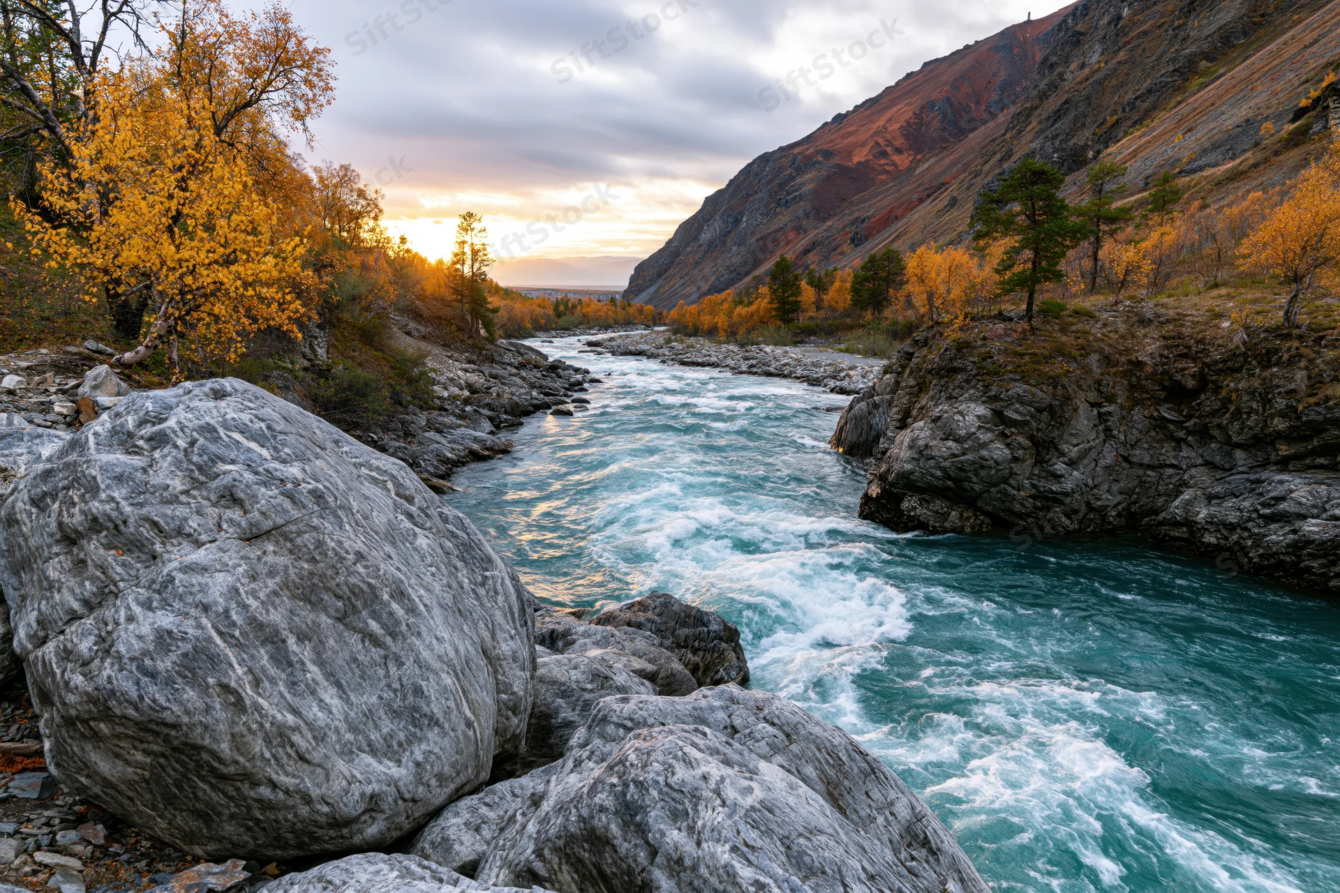 Turquoise river rushing through rocky mountain canyon at sunset with autumn foliage