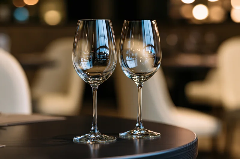 Two empty wine glasses on a dark round table in a restaurant interior