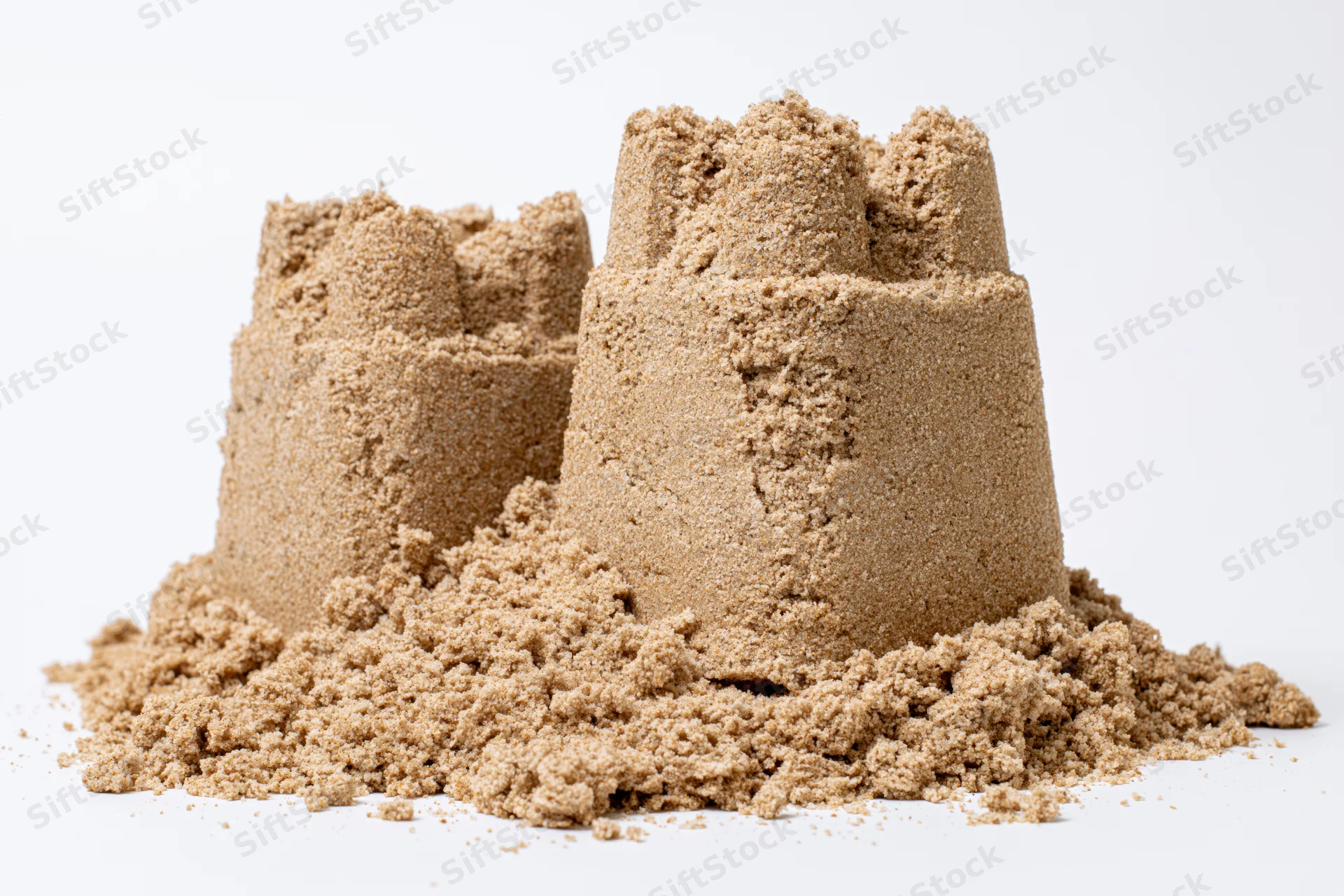 Two handmade sand castles of different heights on a white surface