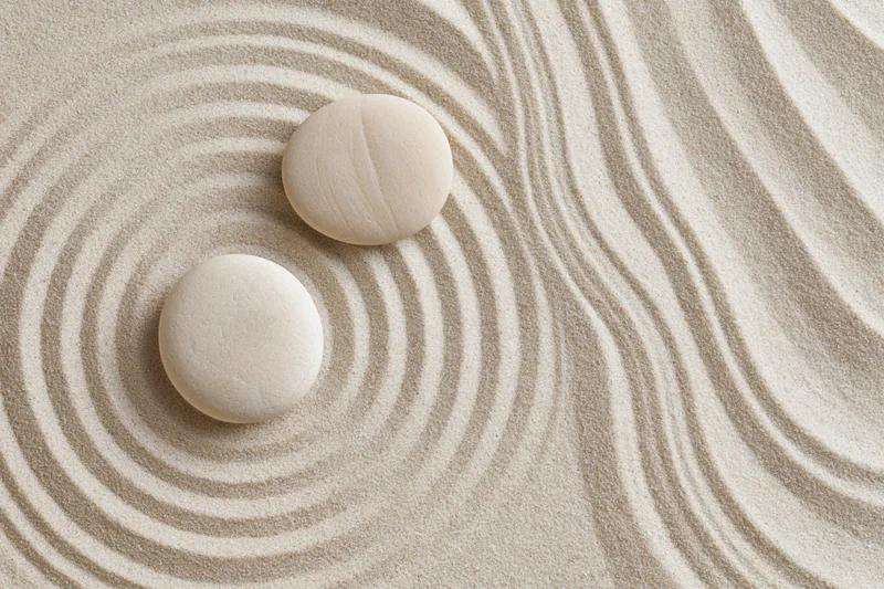 Two smooth white stones resting on raked sand in a zen garden