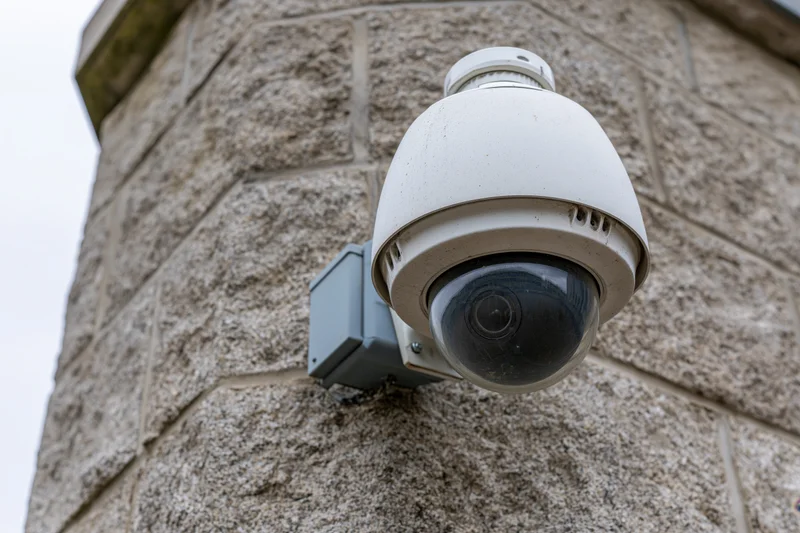 White dome security camera mounted on a stone wall exterior
