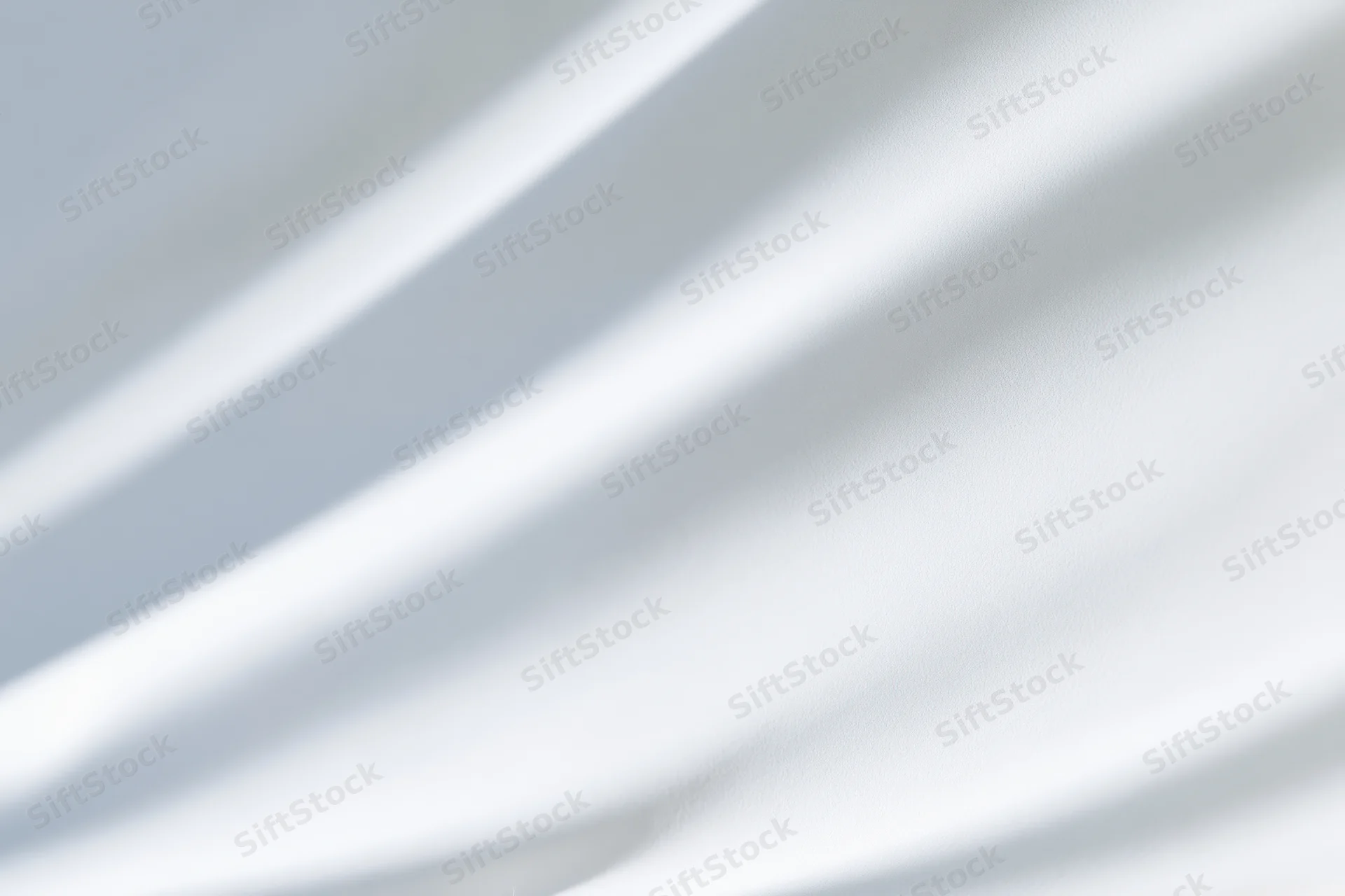 Soft diagonal shadows on a white fabric surface