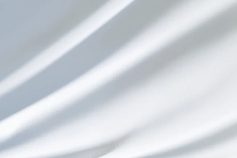 Soft diagonal shadows on a white fabric surface