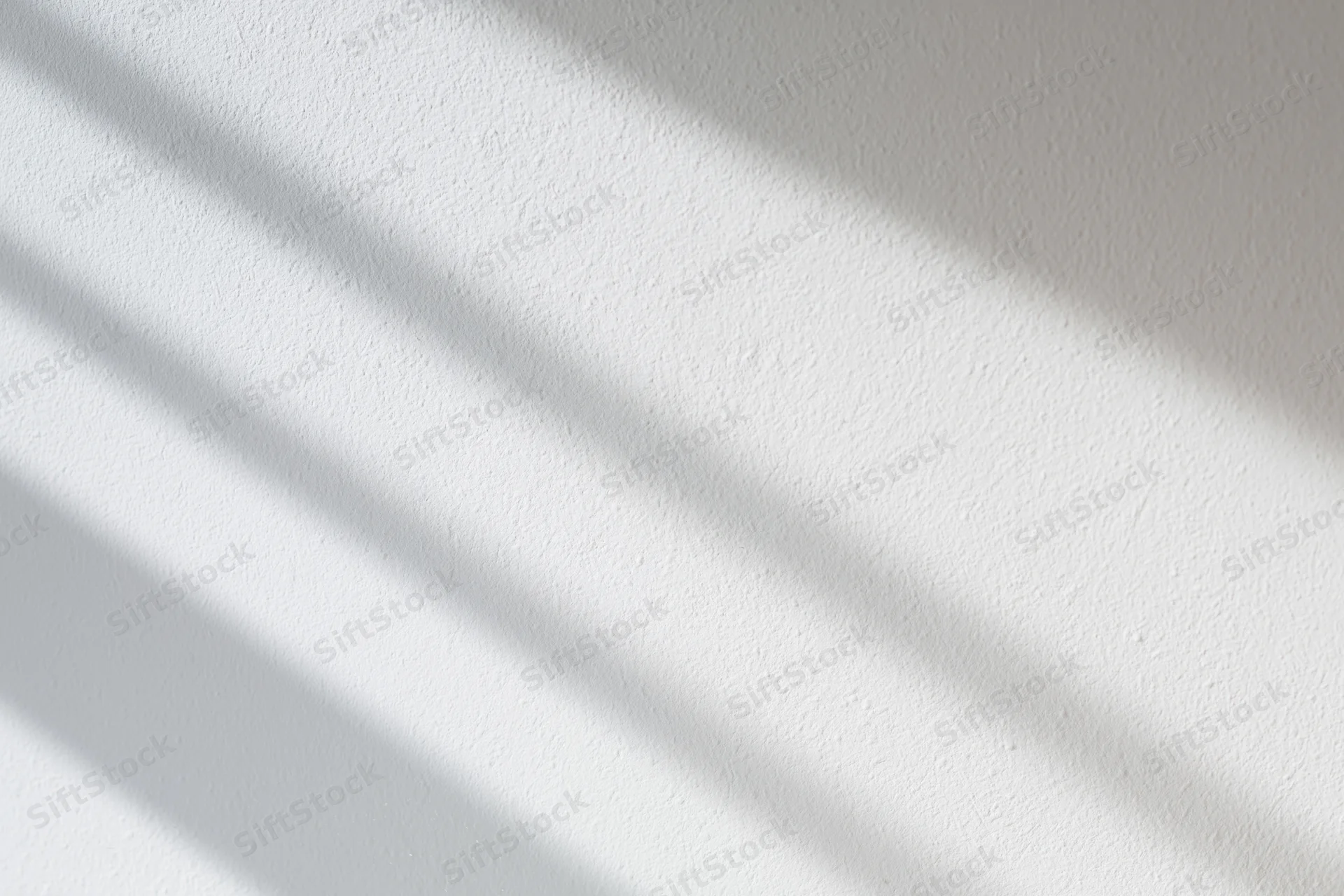 White plaster wall with diagonal shadows from natural light