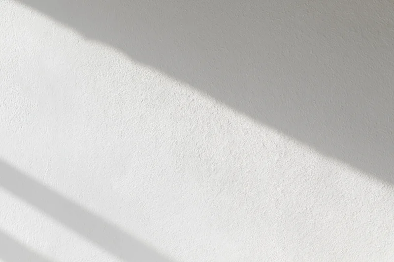 White plaster wall with diagonal shadows from natural light, interior surface
