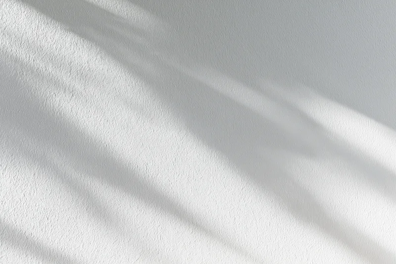 White painted plaster wall with soft diagonal shadows from natural light