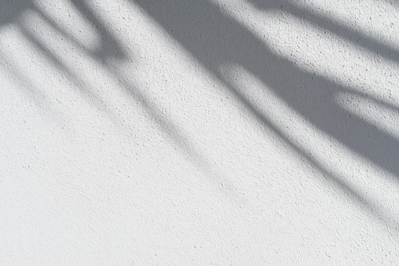 White plaster wall with diagonal shadows from sunlight, interior surface texture