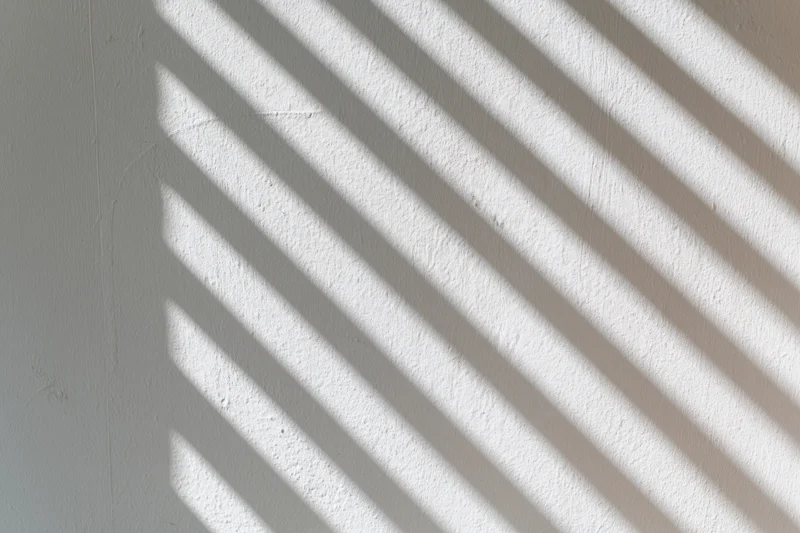 Diagonal light and shadow stripes on a white plaster wall interior