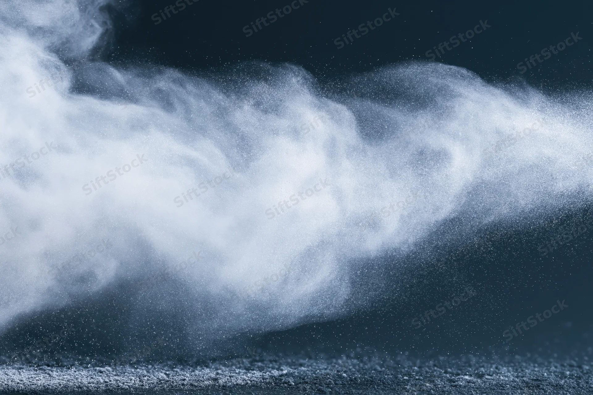 White powder exploding into airborne dust cloud against dark background