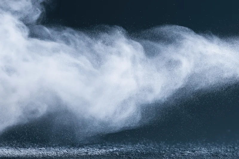 White powder exploding into airborne dust cloud against dark background