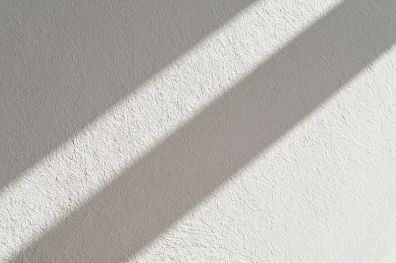 Diagonal shadows on a white textured plaster wall