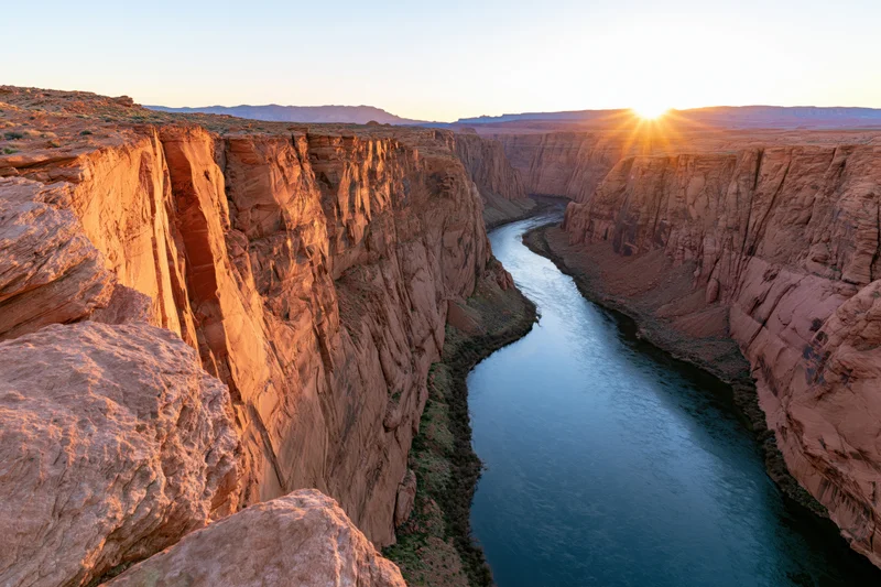 Wide view of a deep canyon with a winding river at sunset from the rim