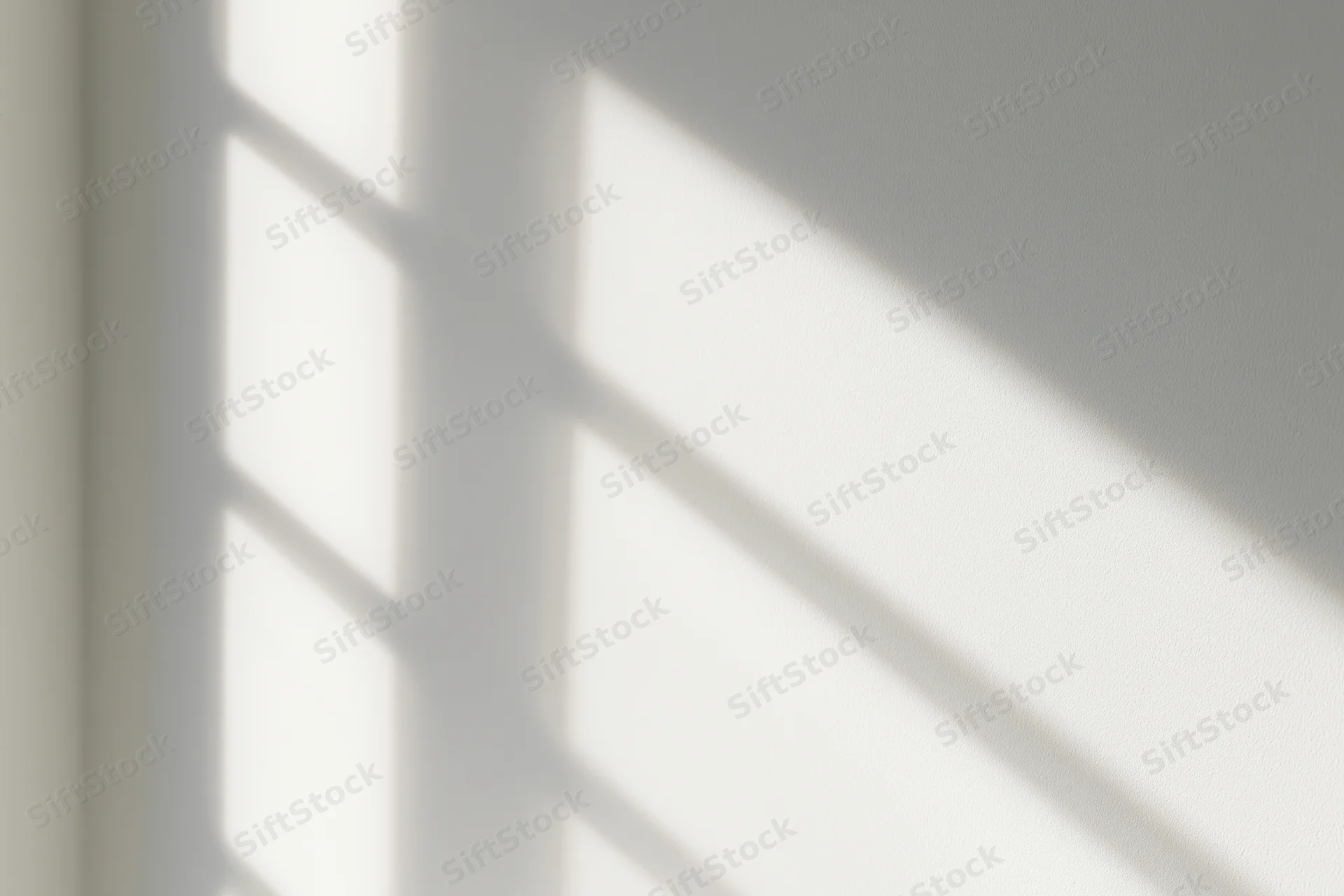 Diagonal shadow pattern from window light on white interior wall