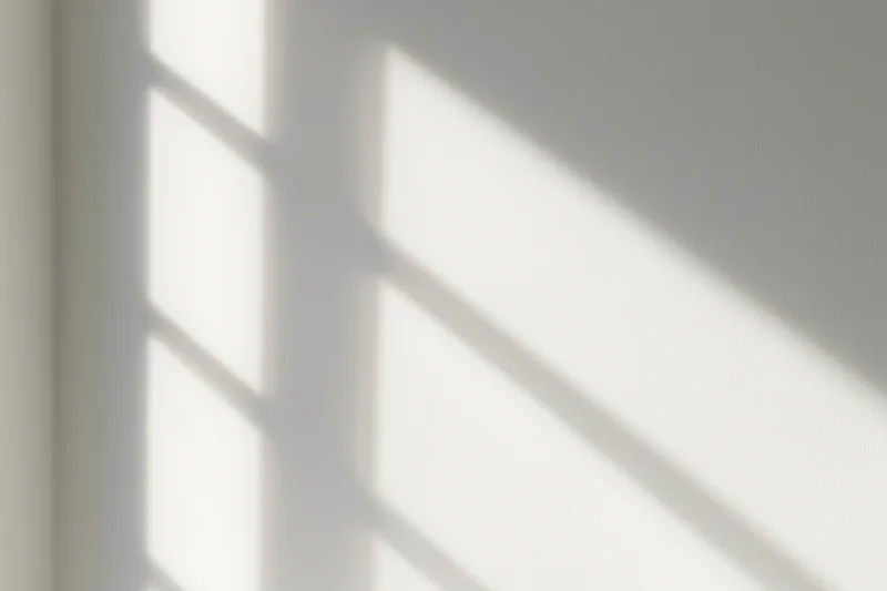 Diagonal shadow pattern from window light on white interior wall