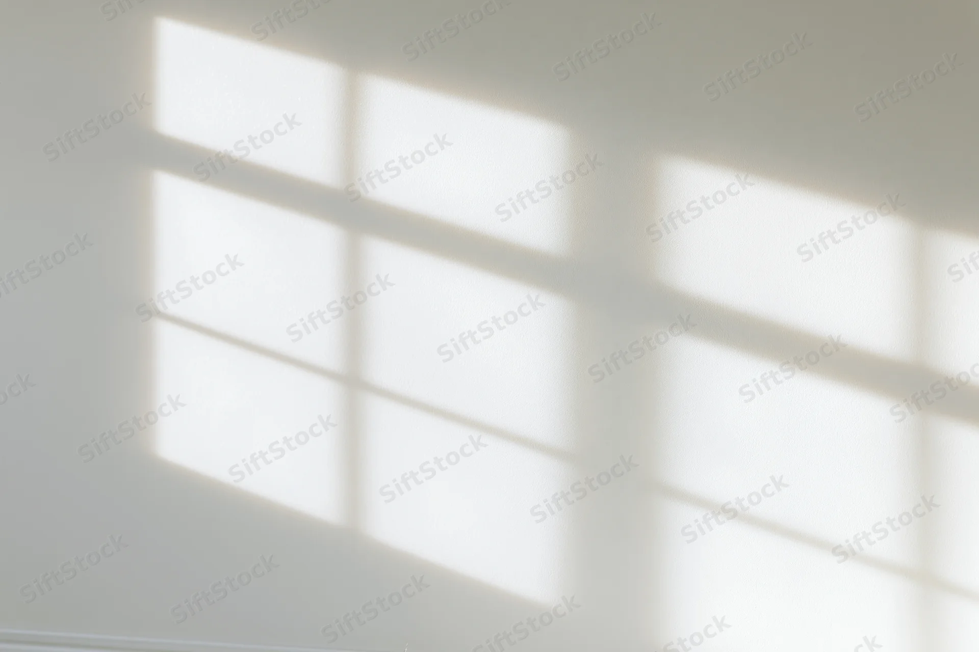 Shadow pattern from window blinds cast across a white interior wall
