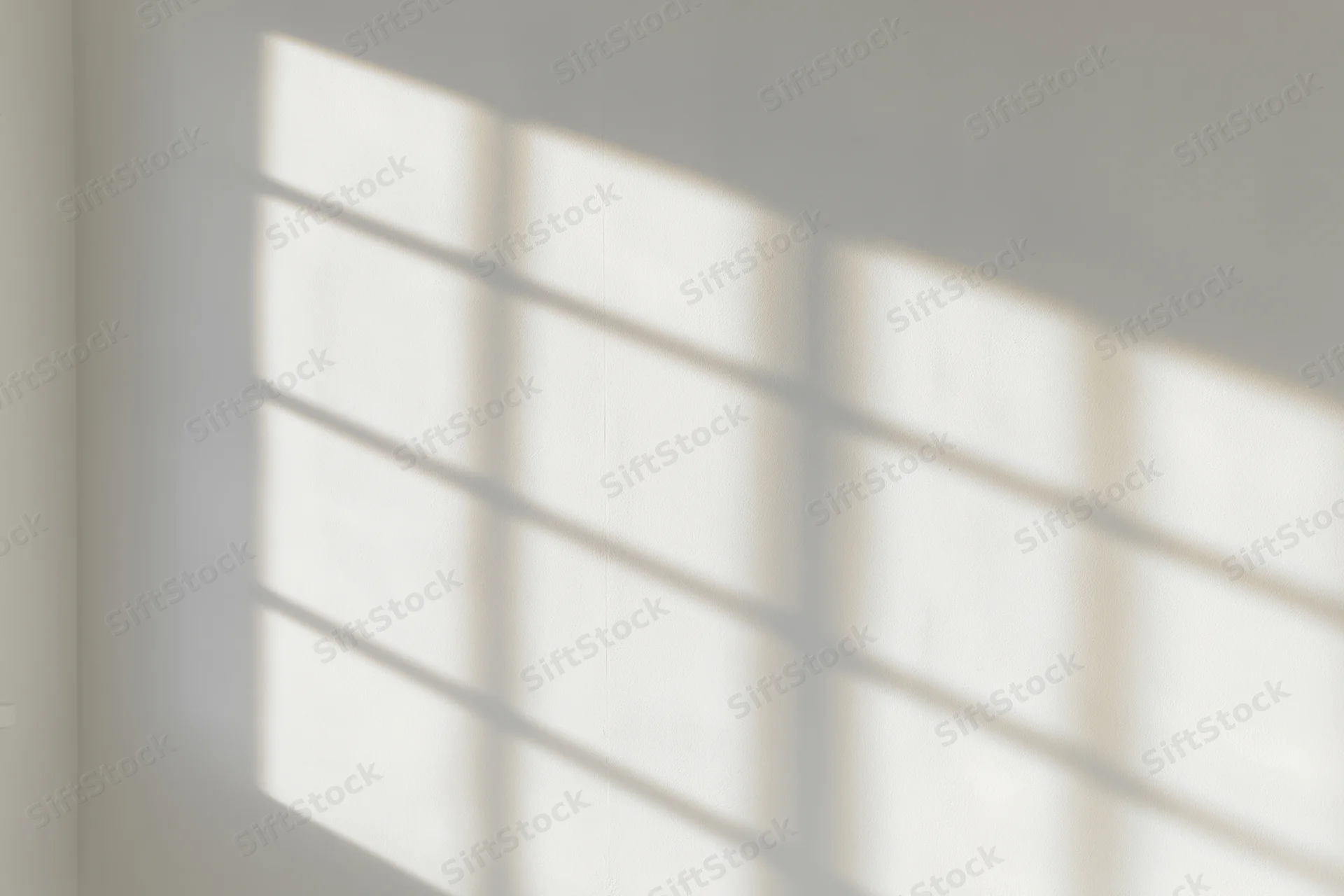 Shadow pattern from window blinds cast on a white interior wall