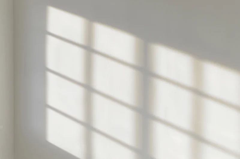 Shadow pattern from window blinds cast on a white interior wall