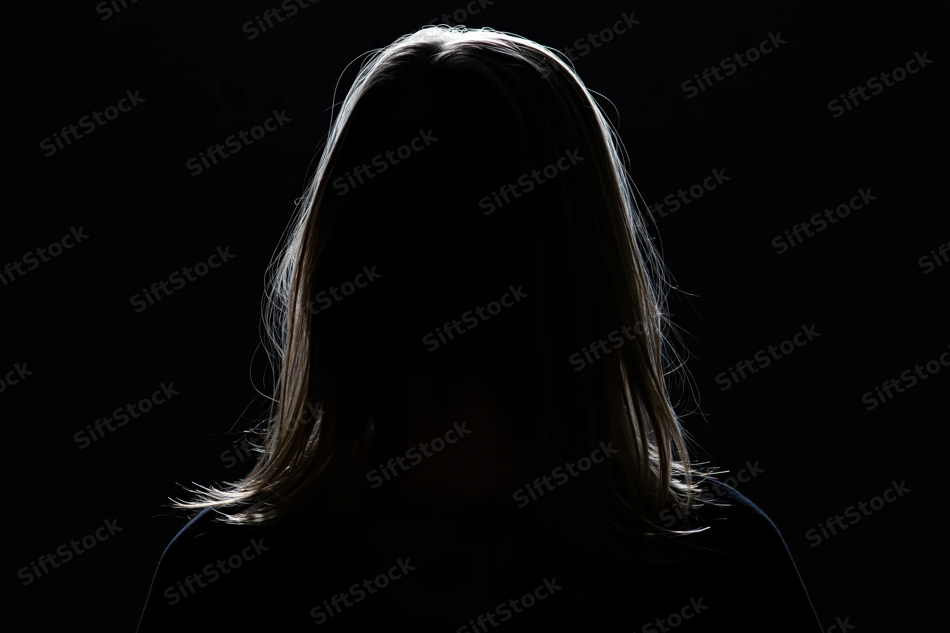 Silhouette of a woman with long hair backlit against black background