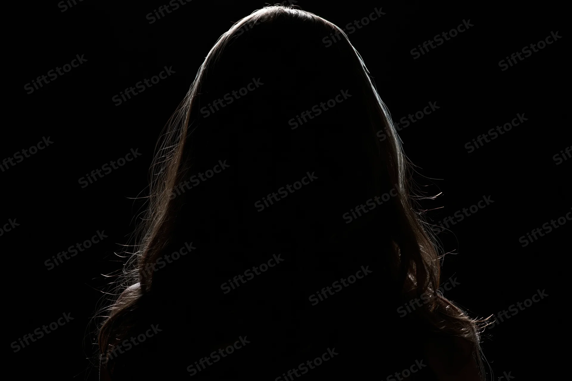 Silhouette of a woman with long hair facing away from the camera against a dark background