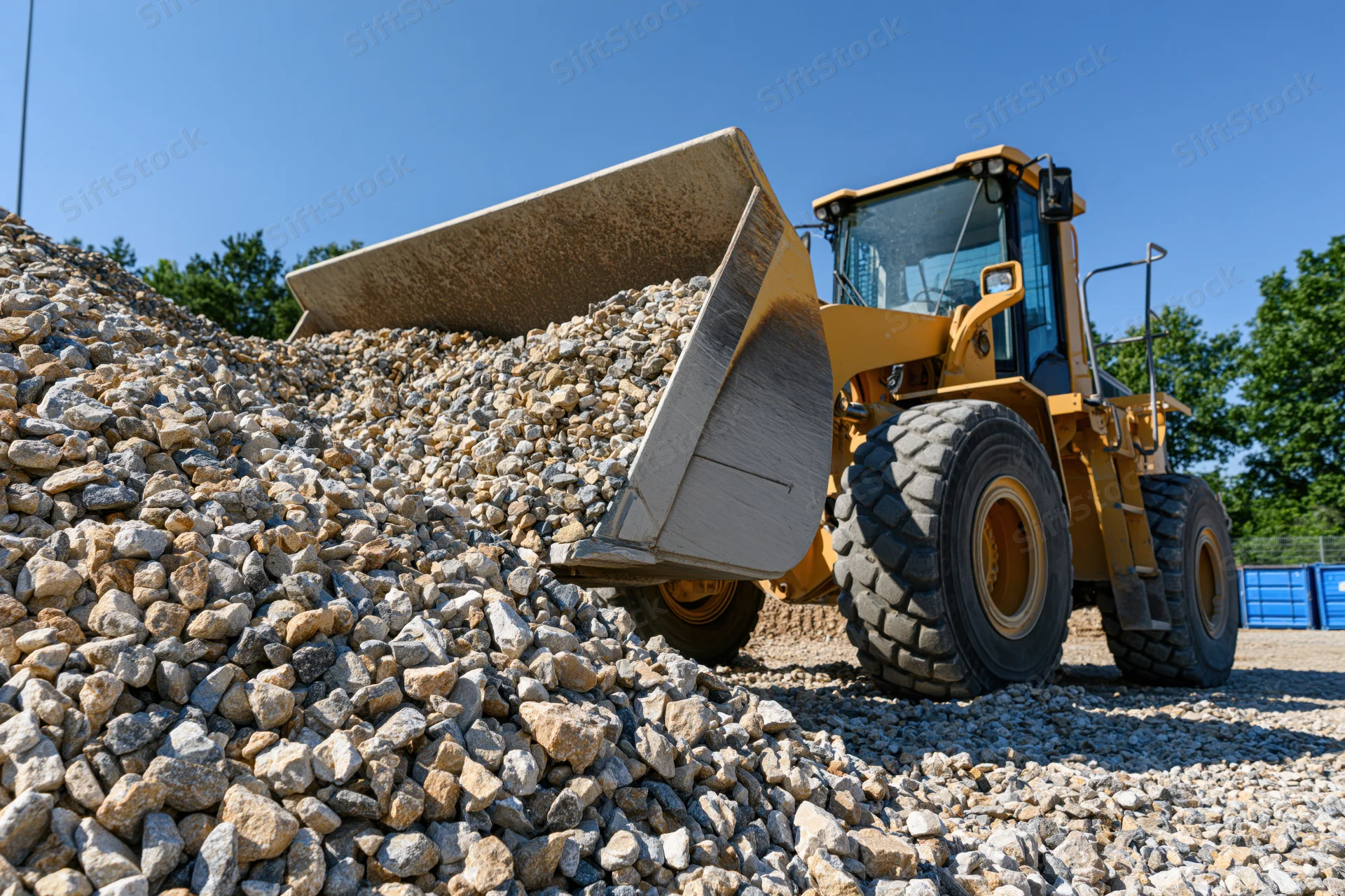 Yellow wheel loader dumping crushed gravel onto a pile at a construction site