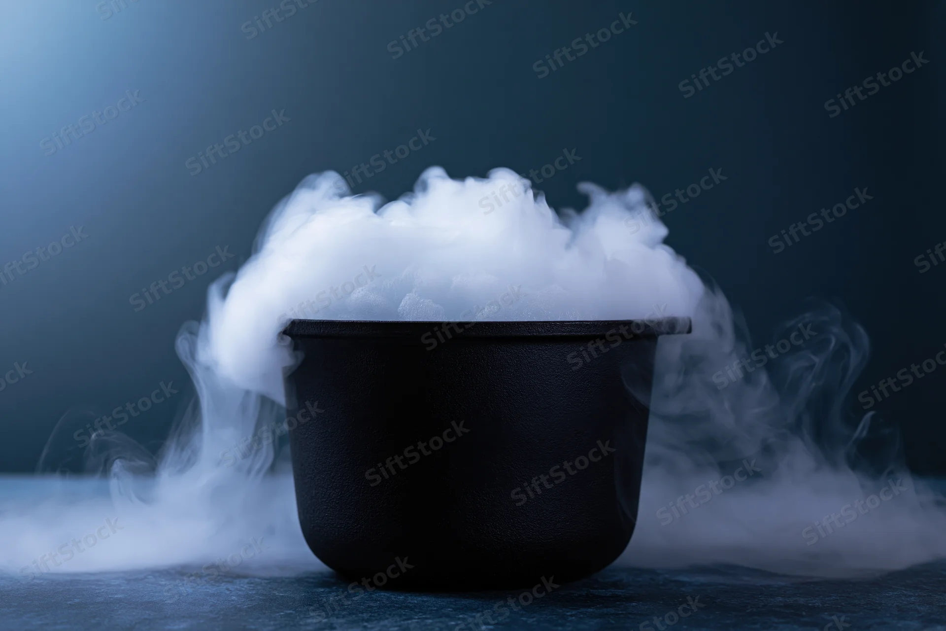 Black cauldron emitting thick white smoke on dark surface