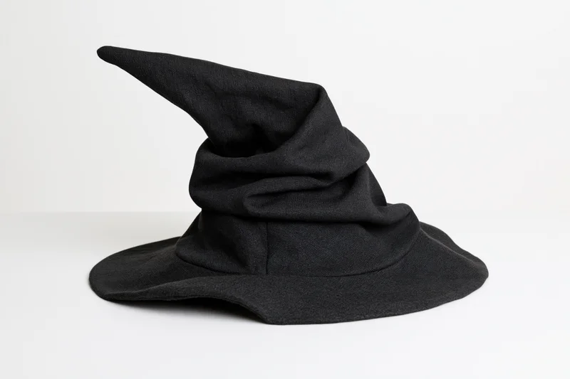 Black fabric witch hat with floppy crumpled pointed crown on white background