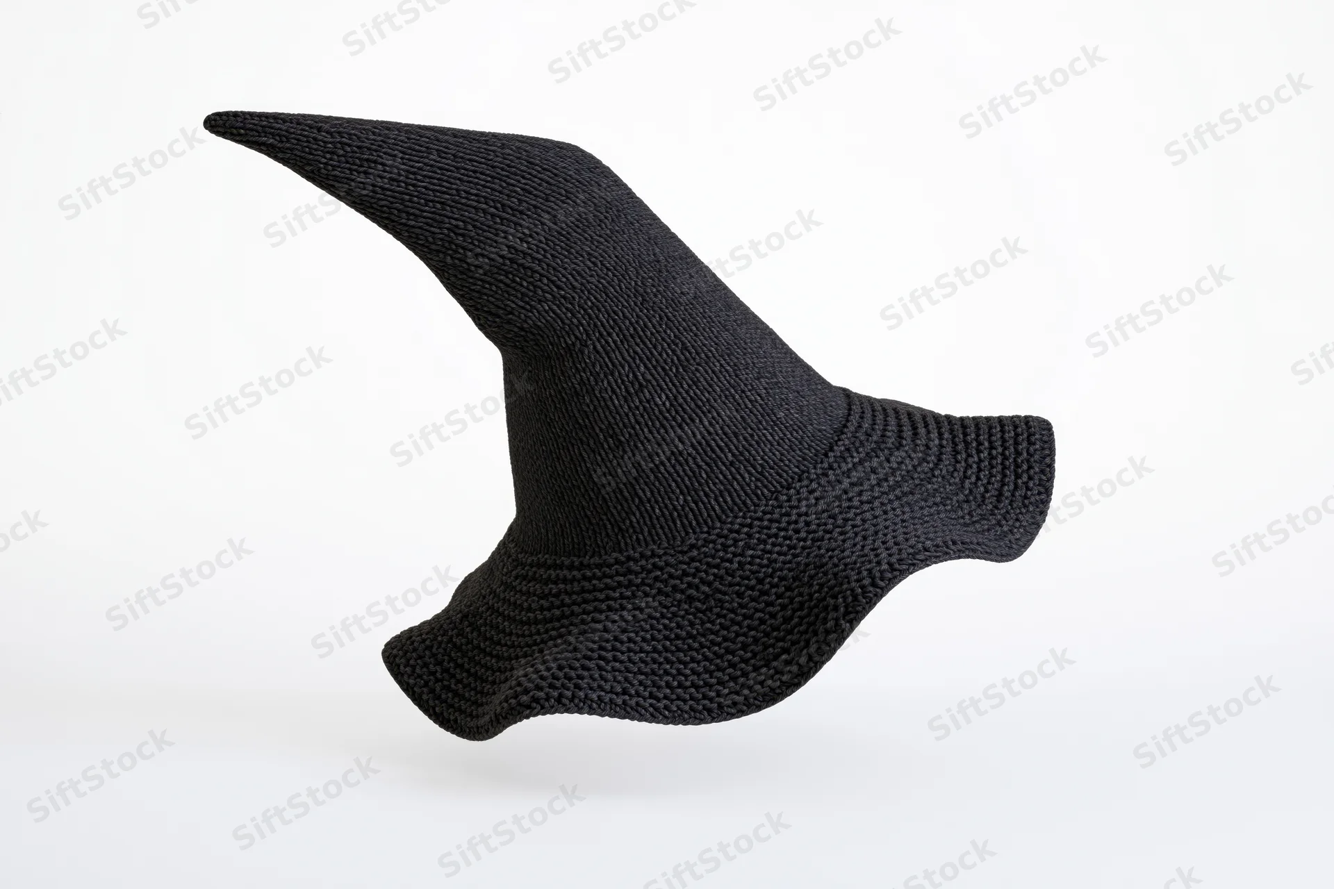Black knitted witch hat with tall pointed peak floating against white background