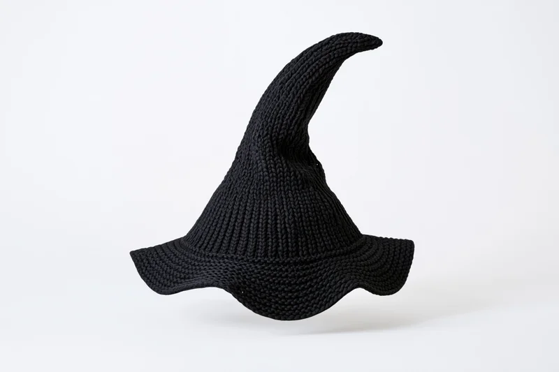 Black knitted witch hat with tall pointed peak isolated on white background
