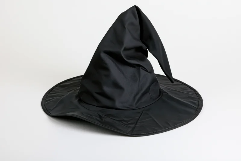 Black pointed witch hat with wide brim and slight bend on white background