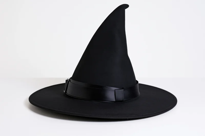 Black witch hat with tall pointed crown and wide brim on white background