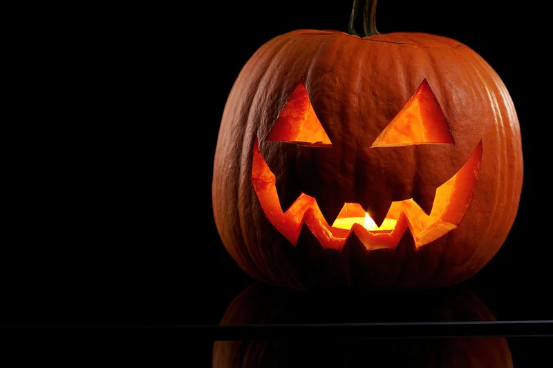 Carved pumpkin with glowing face on black background