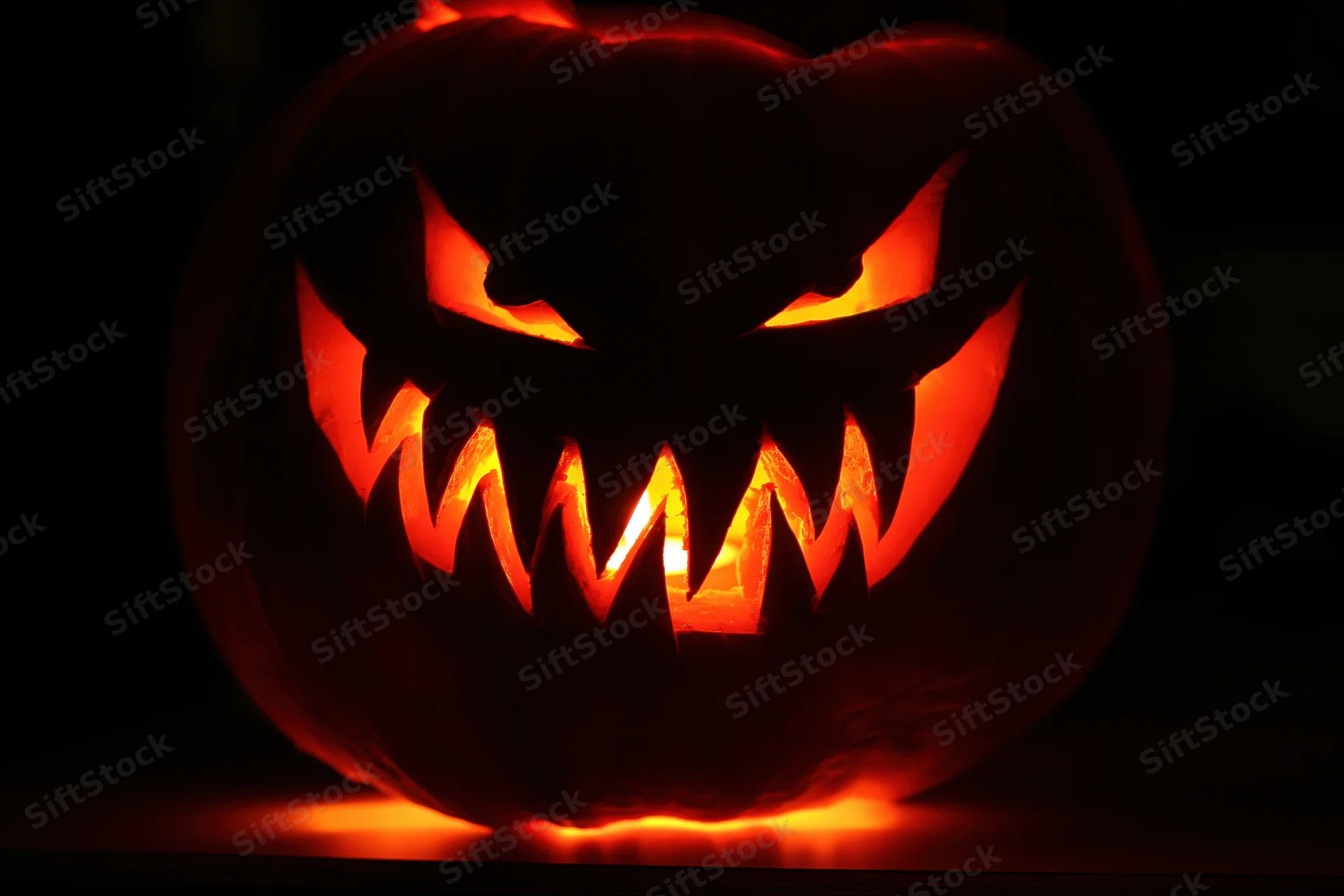 Carved pumpkin with glowing face in darkness
