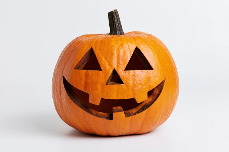 Carved jack-o-lantern pumpkin with smiling face on white background