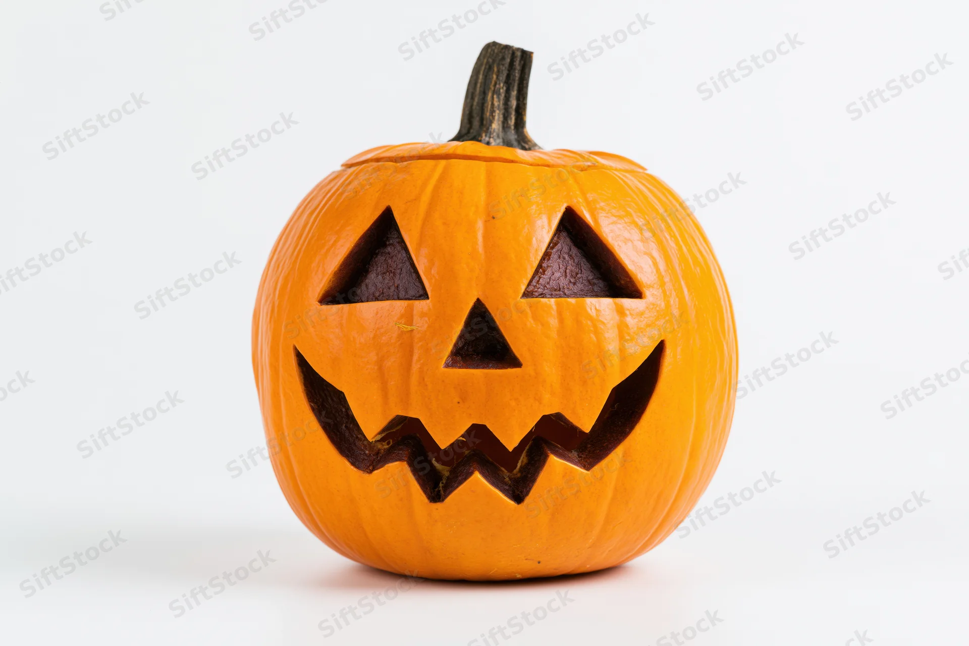 Carved jack-o-lantern pumpkin with triangular eyes and zigzag mouth on white background