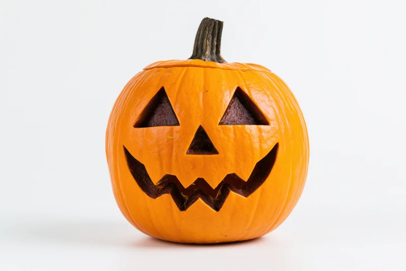 Carved jack-o-lantern pumpkin with triangular eyes and zigzag mouth on white background