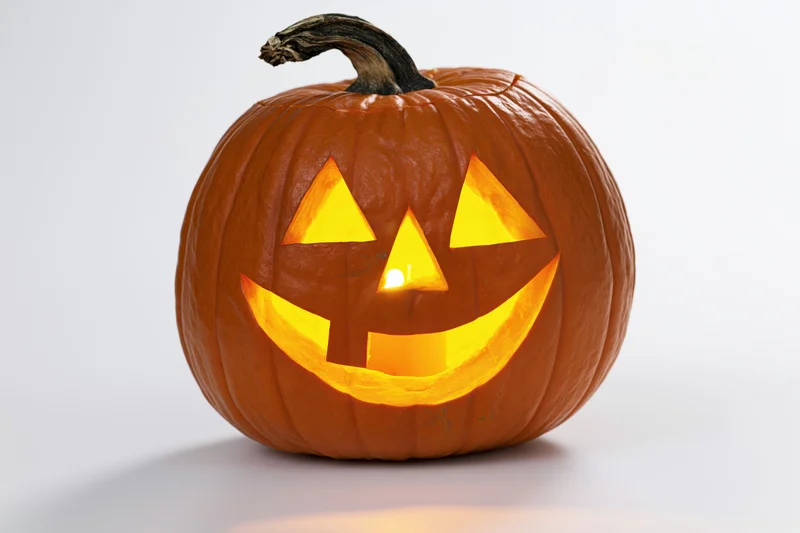 Carved pumpkin with glowing face on white background