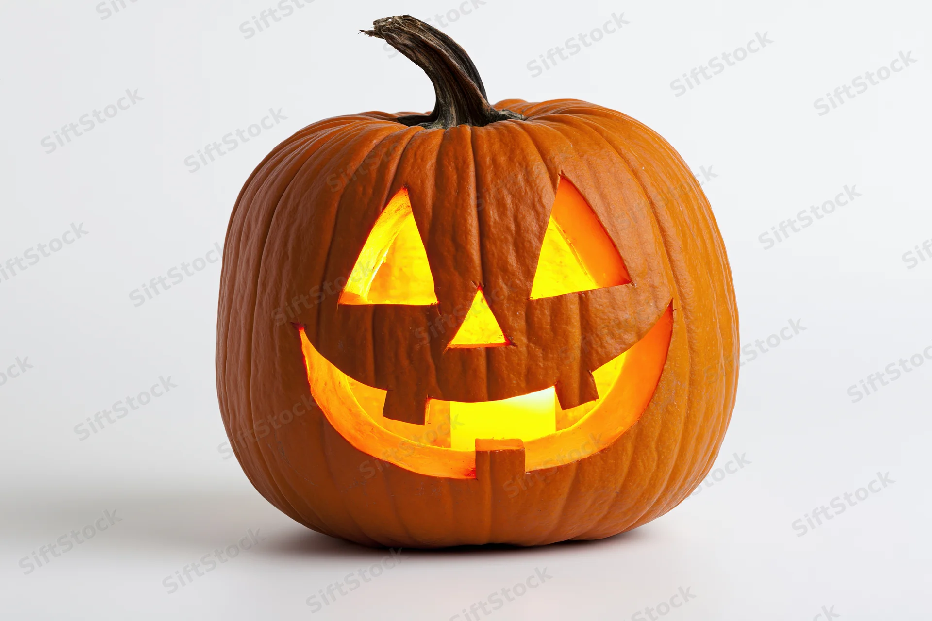Carved pumpkin with glowing face on white background